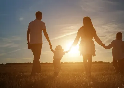 Family walking hand in hand into the sunset