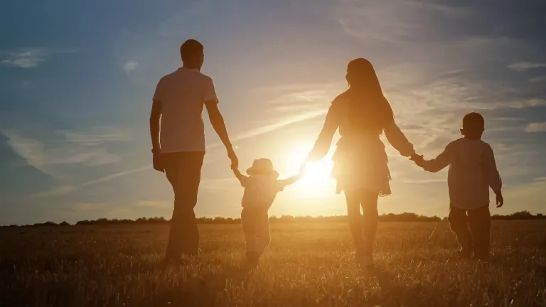 Family walking hand in hand into the sunset