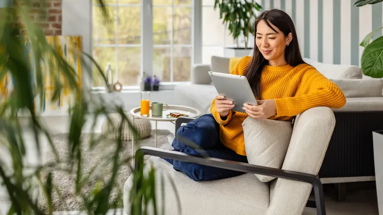 Woman on couch looking at tablet. 